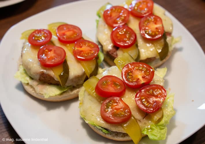 Burger-Patties auf Buns mit Käse-Essiggurkerl-Tomaten